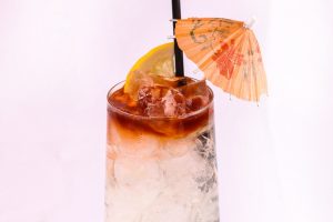 lemon lime and angostura bitters in a cockatial glass with straw and umbrella
