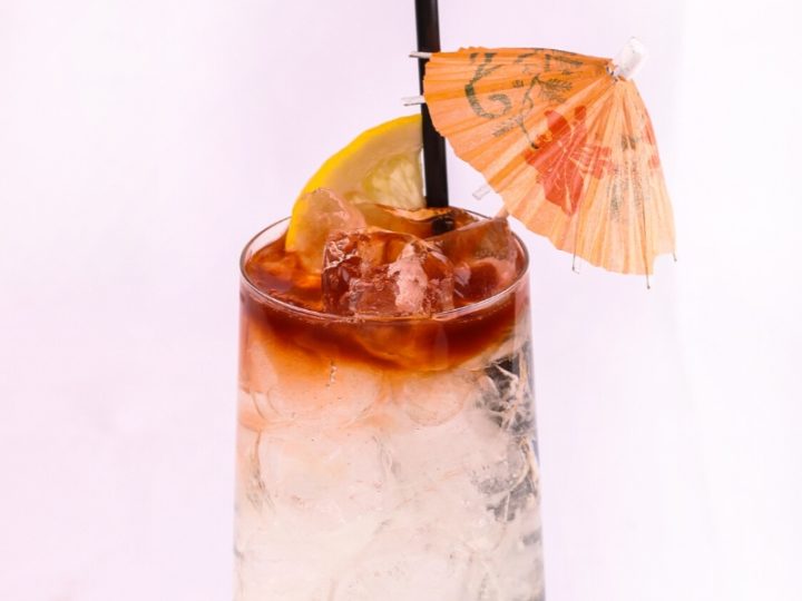 lemon lime and angostura bitters in a cockatial glass with straw and umbrella