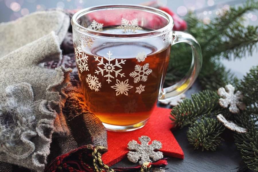 A cup of tea in a festive looking glass cup with christmas decorations