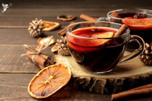 clear thermal cup of swedish glogg mulled wine on a rustic log setting
