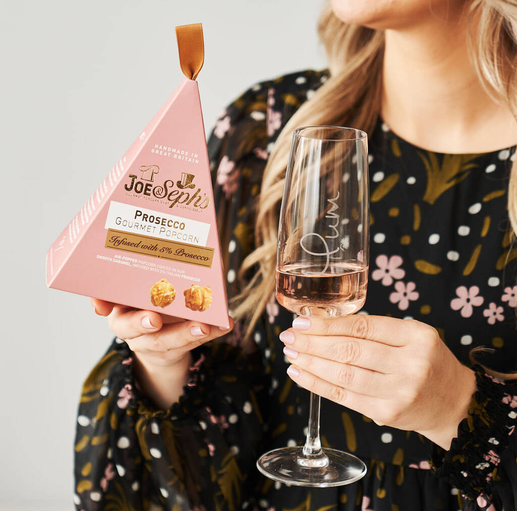 woman holding box of chcolates and glass of prosecco rose