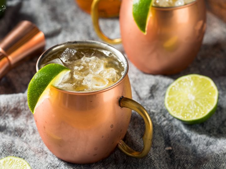 two copper mugs filled with ice and refreshing irish mule cocktail topped with lime wedge