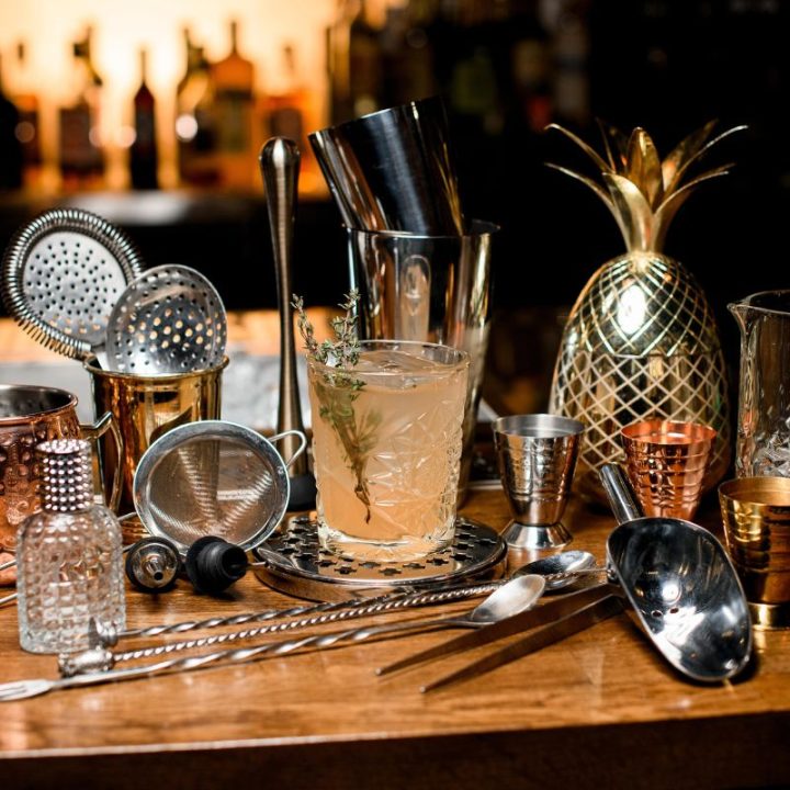 Elegant cocktail setup with bar tools, glassware, and a golden pineapple