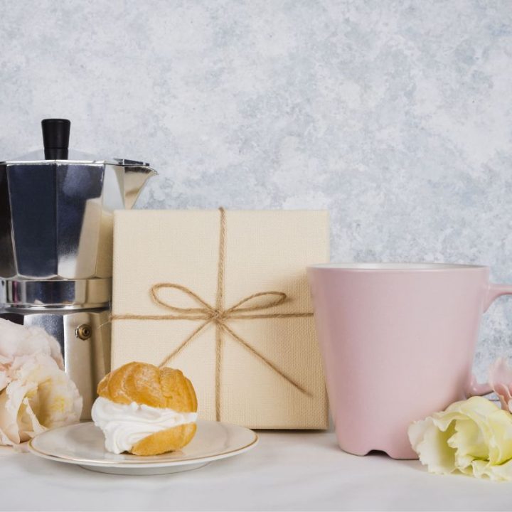 Coffee gift set with moka pot, pink mug, flowers, and pastry