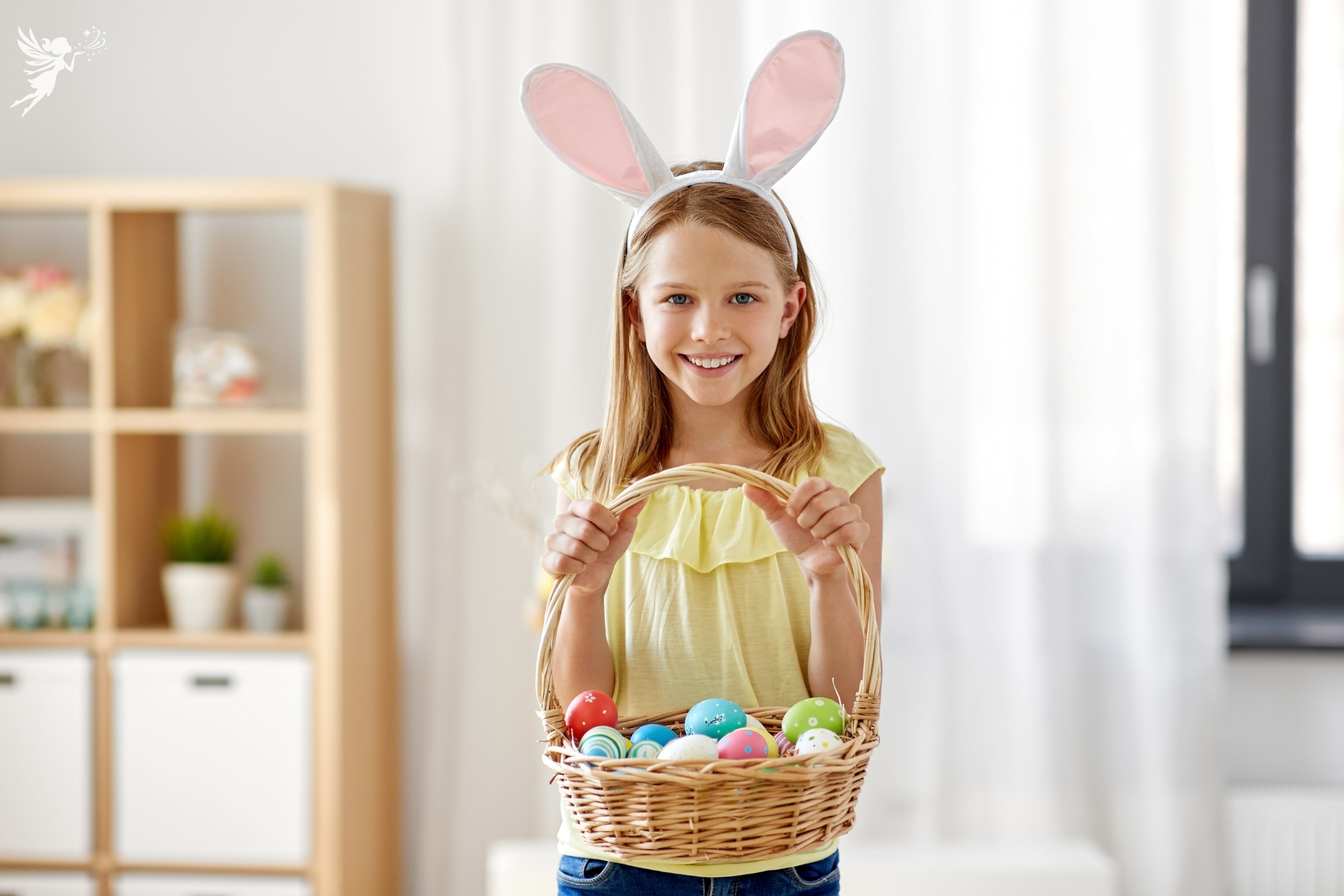 a cute girl in yellow tshirt and bunny ears holding a basket of easter eggs