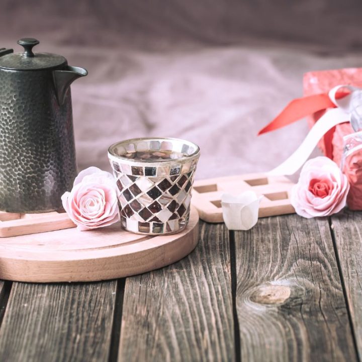 Rustic tea setup with metal teapot, mosaic cup, and gift