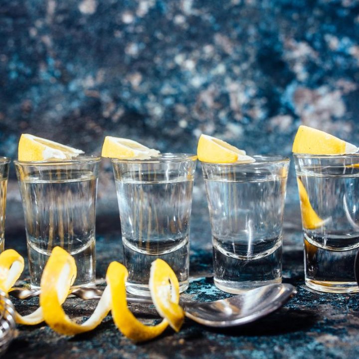 Five tequila shots with lemon wedges and bar accessories displayed