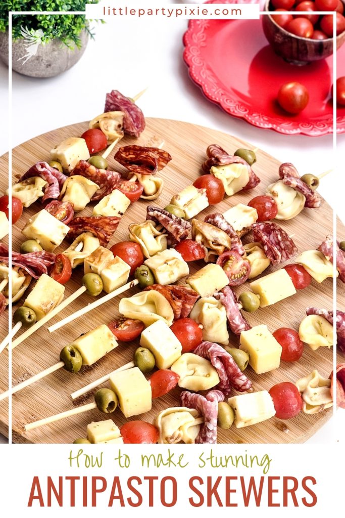 Antipasto skewers with cheese cubes, salami, tortellini, olives, and cherry tomatoes on wooden board.