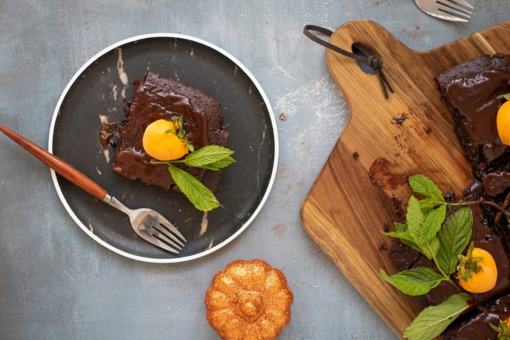 A slice of finished recipe of Chocolate Pumpkin Patch Brownie Cake in a plate with fork ready for serving