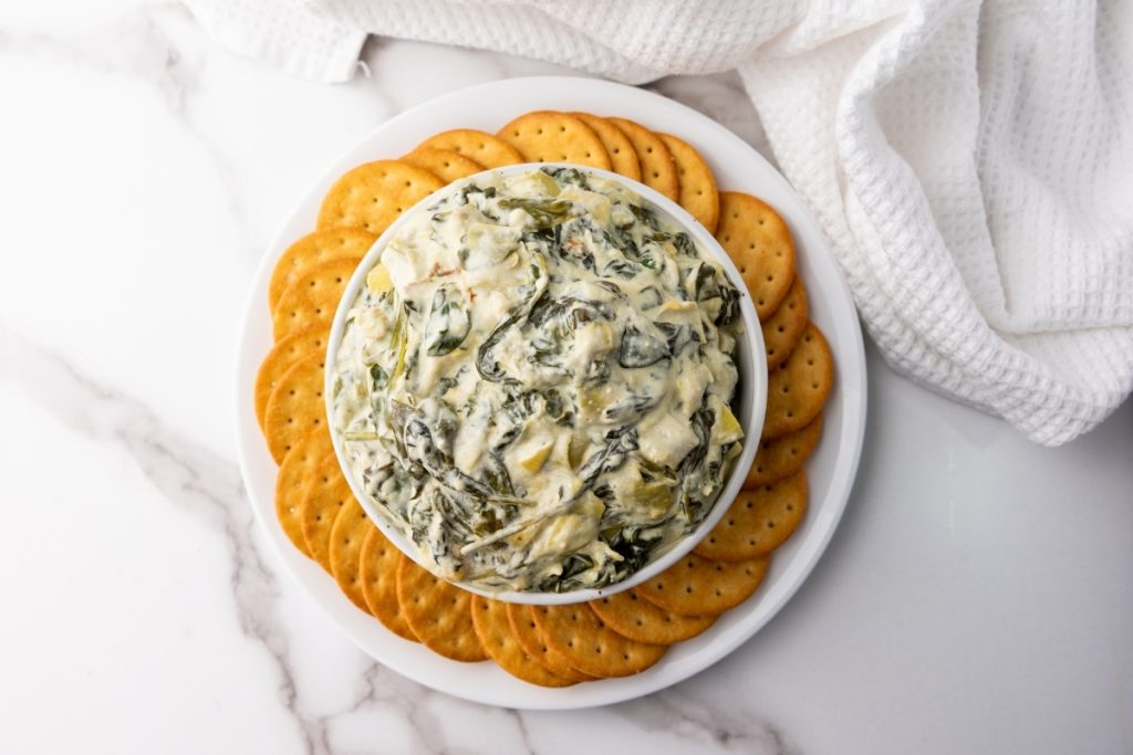 Spinach Artichoke Dip served in white plate with crackers