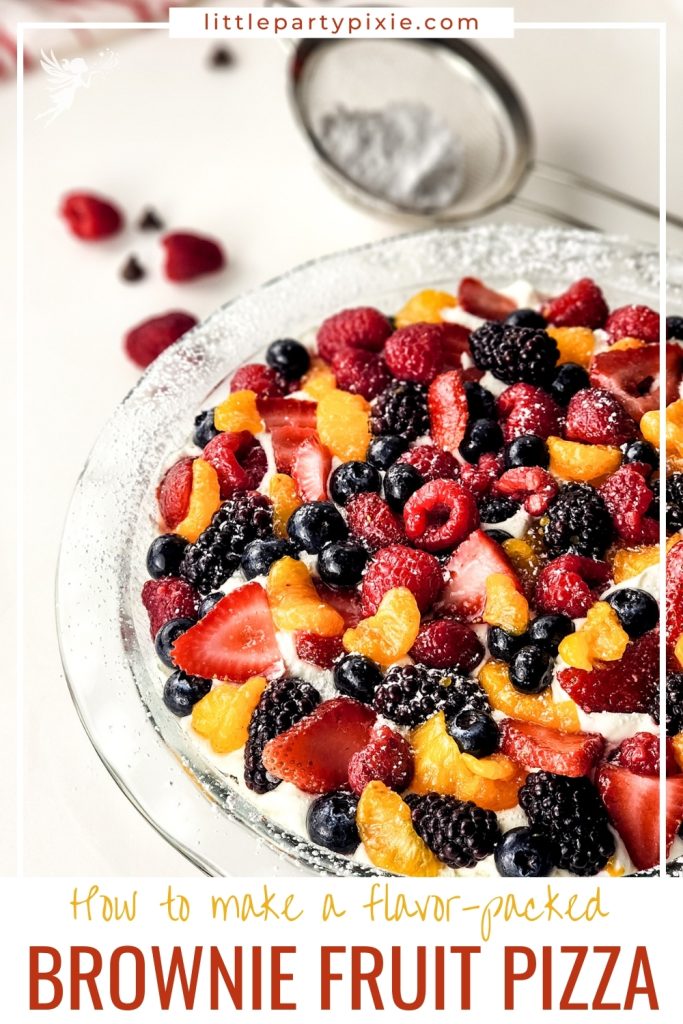 Colorful brownie fruit pizza topped with strawberries, blueberries, raspberries, blackberries, mandarin oranges, and powdered sugar.
