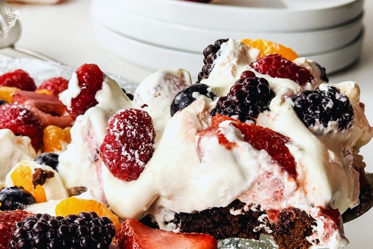 Colorful brownie fruit pizza topped with strawberries, blueberries, raspberries, blackberries, mandarin oranges, and powdered sugar.