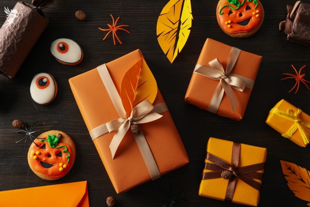 orange wrapped gifts on a dark background with cut out fall leaves and pumpkin cookie decorations for halloween