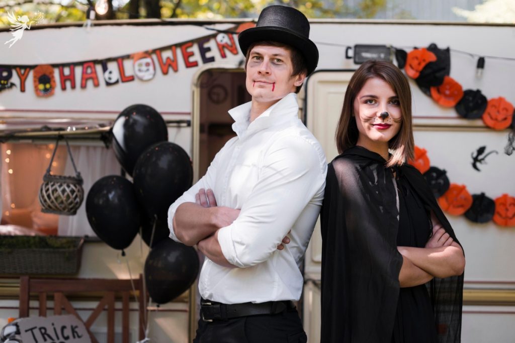 Halloween costume couple in front of a camper with halloween decorations