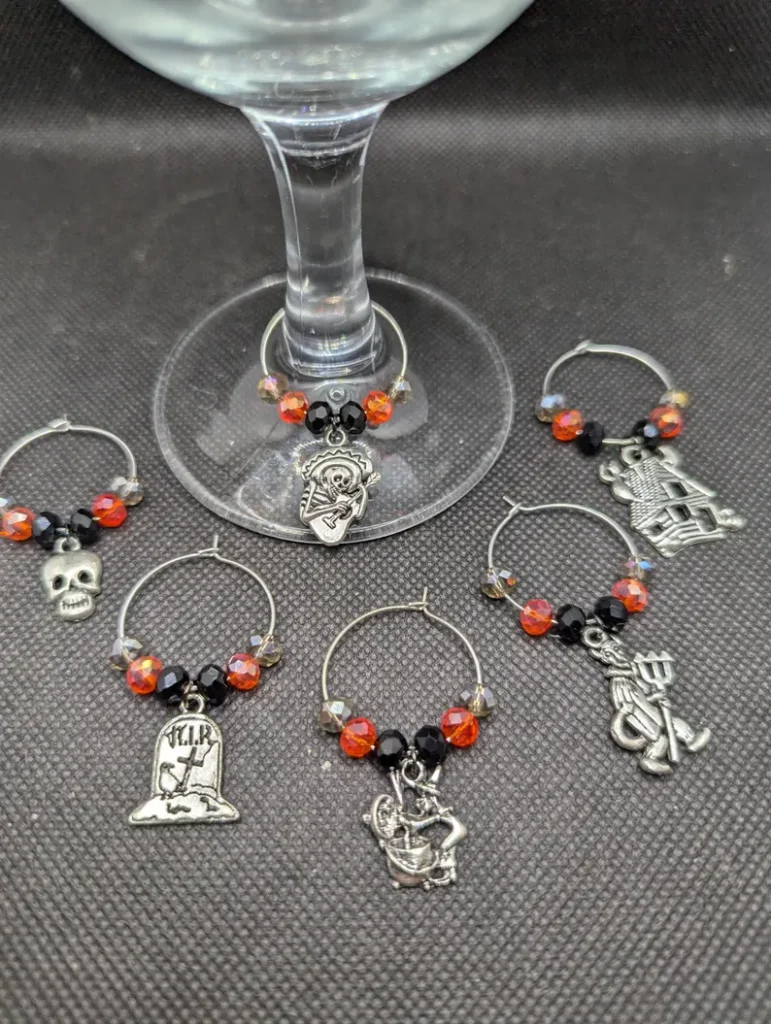 halloween themed silver glass charms with black and organge beads on the base of a stemmed wine glass - gift idea on etsy
