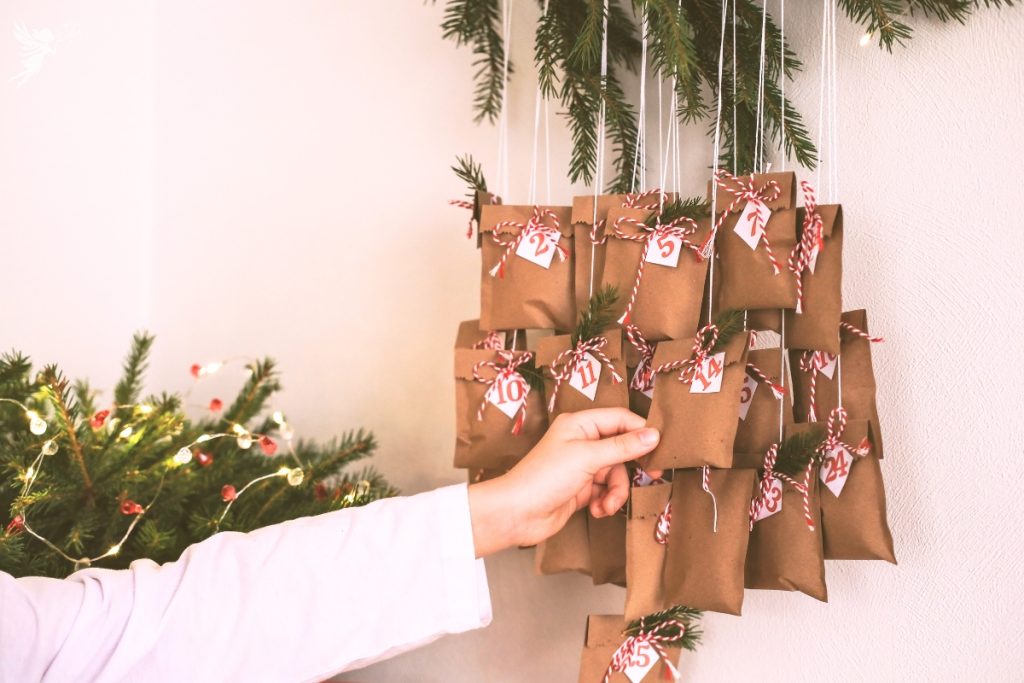 a bunch of small numbered bags hanging from a tree with a hand pulling one off