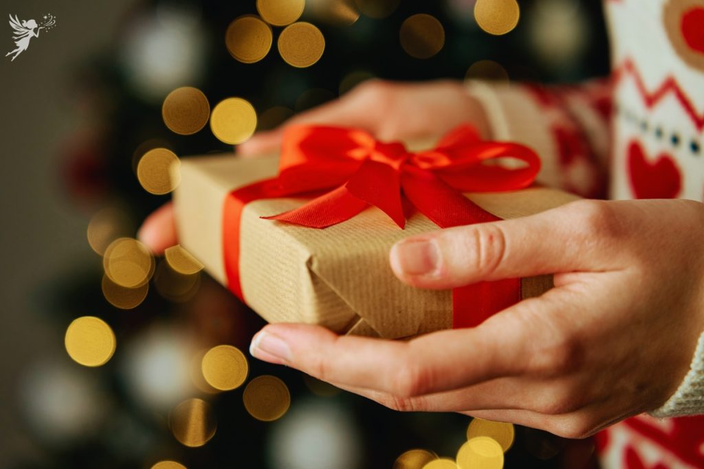 woman handing over a christmas gift wrapped in brown paper and red ribbon