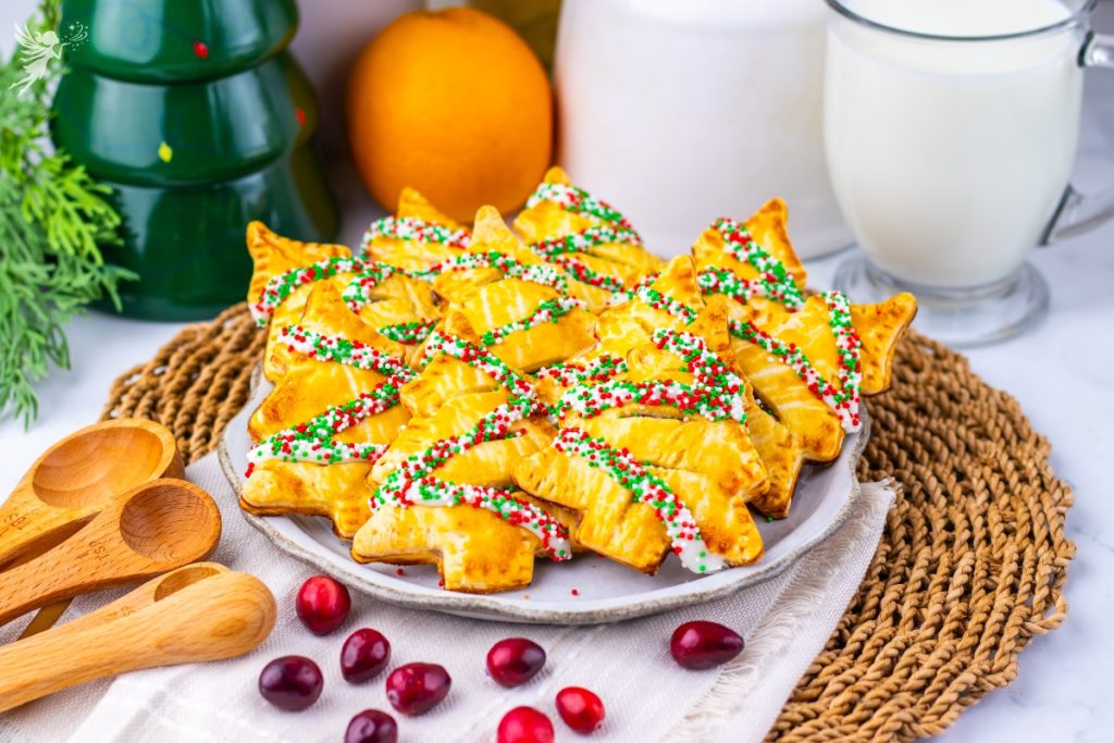 Beautiful shot of golden-brown Christmas Tree Cranberry Orange Hand Pies dusted with festive red, white, and green sprinkles.