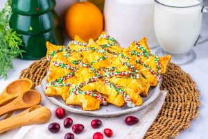 Beautiful shot of golden-brown Christmas Tree Cranberry Orange Hand Pies dusted with festive red, white, and green sprinkles.