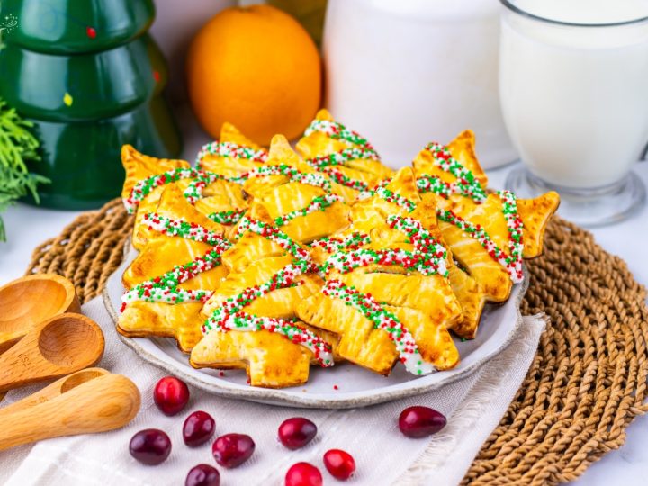 Beautiful shot of golden-brown Christmas Tree Cranberry Orange Hand Pies dusted with festive red, white, and green sprinkles.