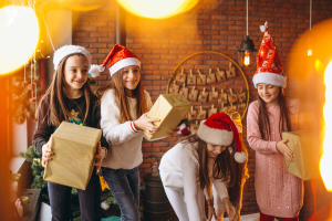 pre teen girls picking u christmas packages dressed in santa hats