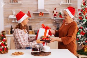 an older and younger lady swapping christmas gifts in a kitchen