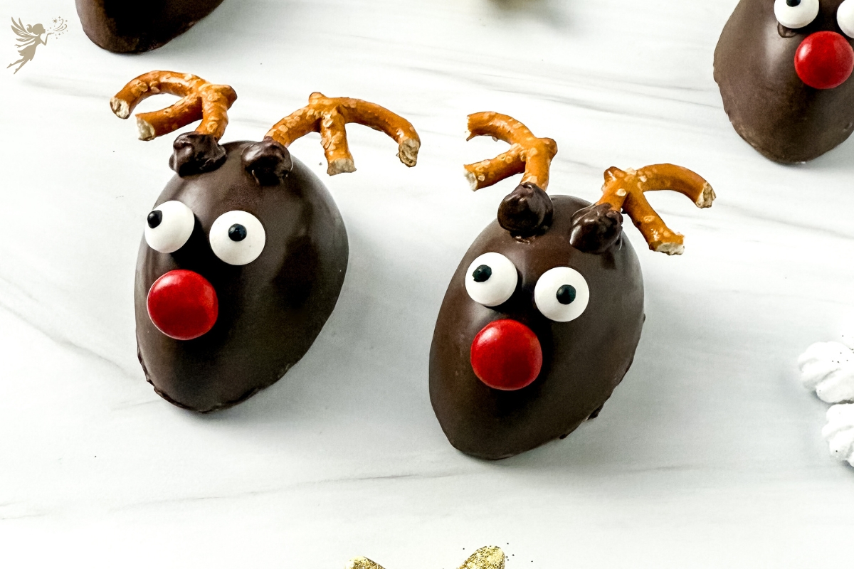 Two shiny, Rudolph chocolate dipped marshmallow heads with googly eyes, pretzel antlers, and bright red candy noses.