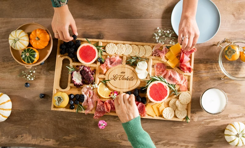 flatlay of hands reaching for food in a long rectangular cheese tray etsy