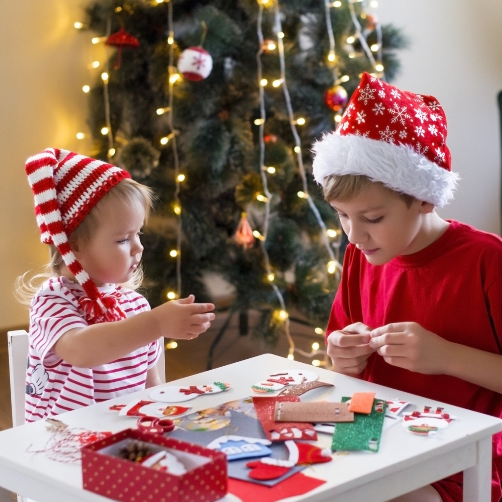 small children crafting goether on a little table in christmas clothing