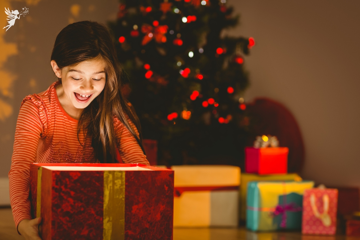 girl opening a red christmas box with surprise as light shines out of the box