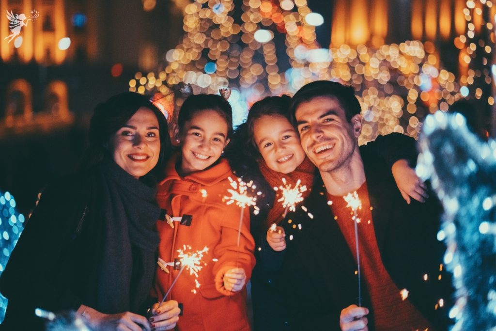 family in winter wear with glowing sparklers for new year