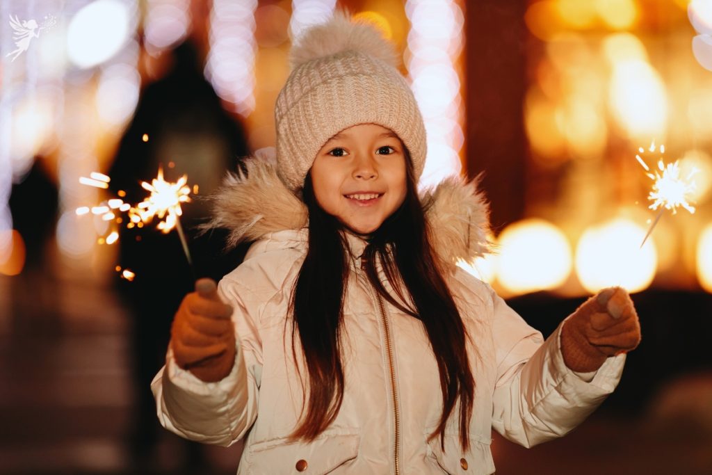 girl rugged up in white winter jacket and clothing waving sparkler