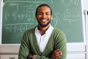 Male teacher in front of blackboard with algebra equations