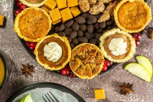 An elegant Mini Pie Dessert Platter featuring various mini pies, candies, candied nuts, and fresh cranberries.
