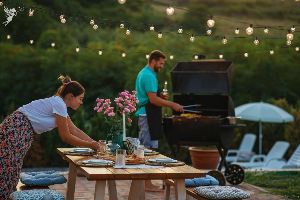 c couple preparing an outdoor bbq setting the table and firing up the grill