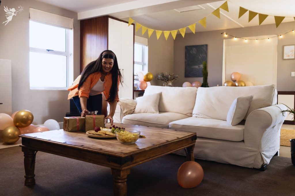 a woman setting presents and snacks in a neat but simply decorated room for a party