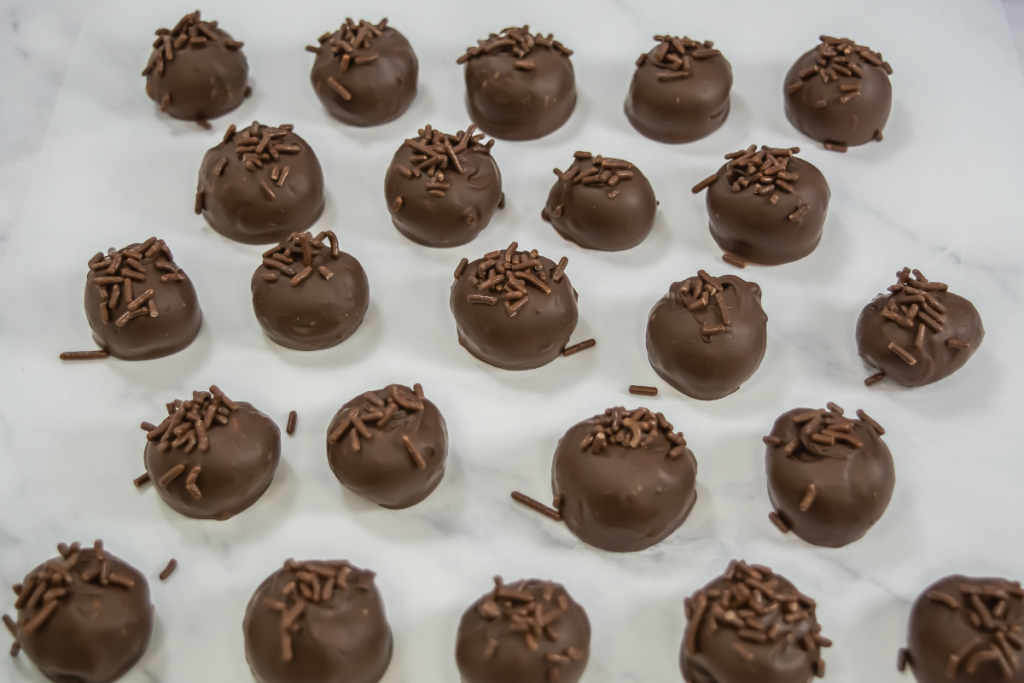 A close-up view of the finished Baileys Chocolate Truffles, coated in milk chocolate and generously topped with chocolate sprinkles.
