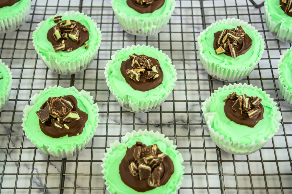 Finished Mini Mint Cheesecakes arranged on a wire cooling rack, featuring the bright green cheesecake, chocolate ganache, and chopped Andes mints topping.