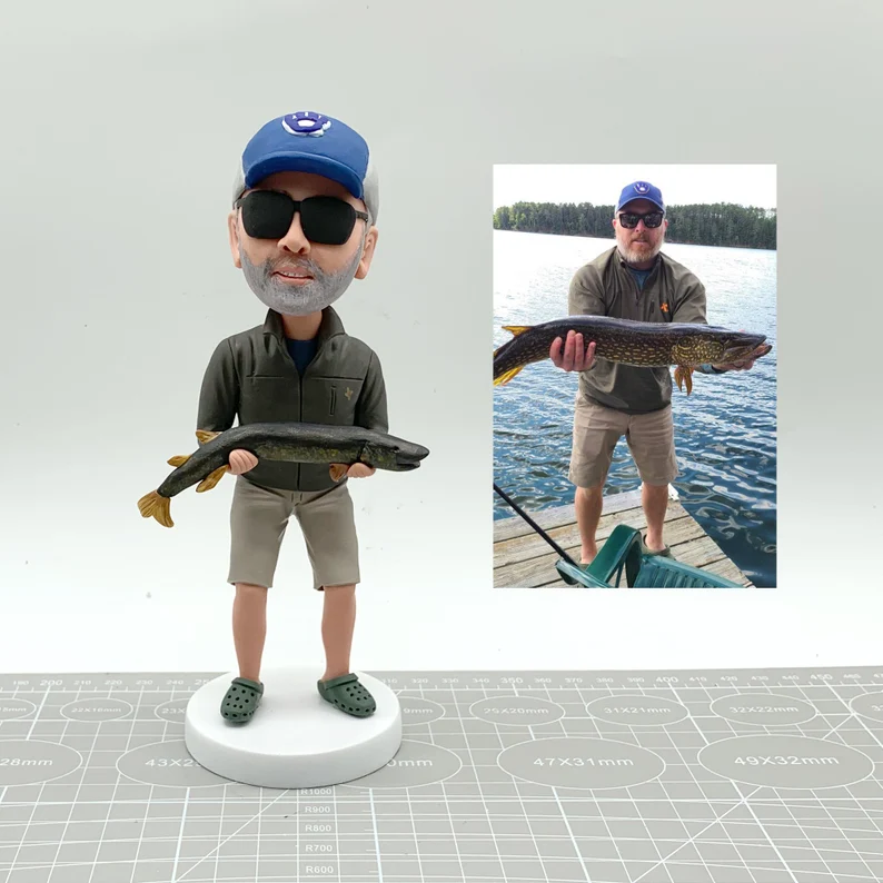 a custome bobblehead doll made from a photo of a man holding a fish etsy