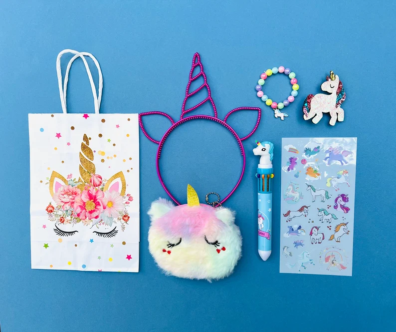 A flat lay of seven assorted items, including a unicorn headband, stickers, and bracelet, packaged as Unicorn Party Favors. Etsy