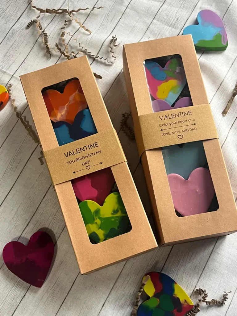 Two brown craft boxes containing chunky, multicolored heart-shaped crayons, a creative and non-candy option for Valentine's Day Party Favors. Etsy