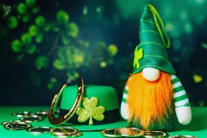 Leprechaun with green hat horse shoe, four leaf clover and lucky coins signifying St Patrick's Day