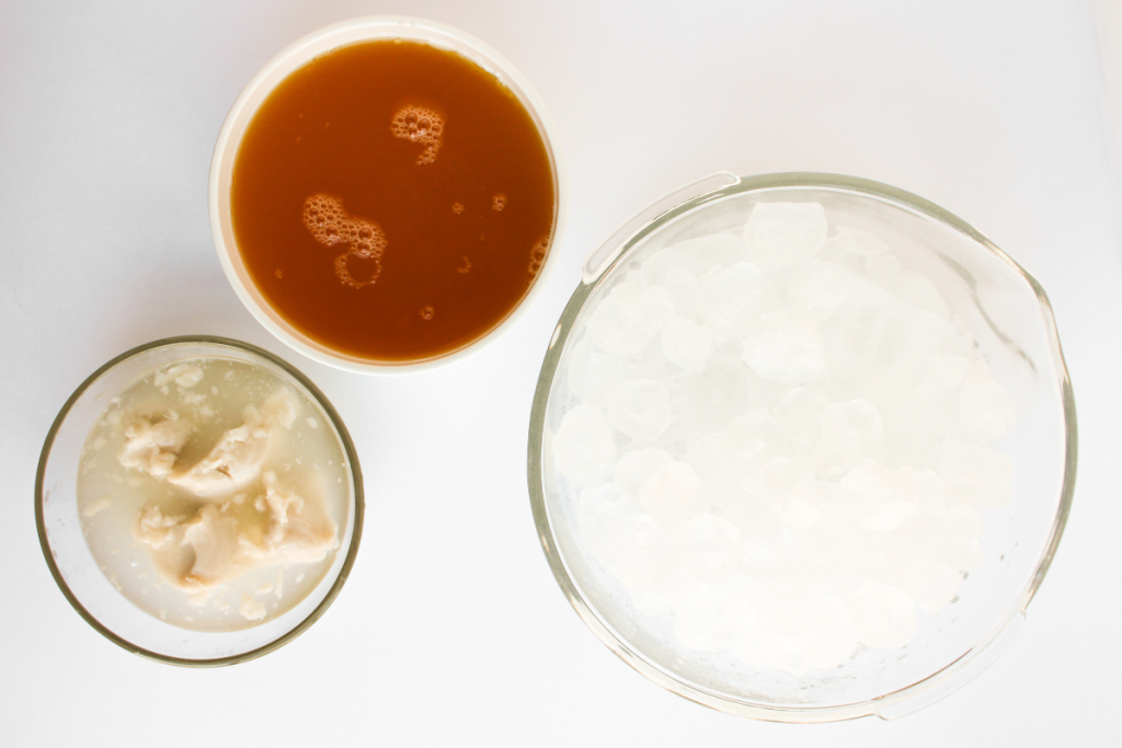 Overhead view of the simple ingredients needed for a tropical Virgin Piña Colada: pineapple juice, coconut cream, and ice.