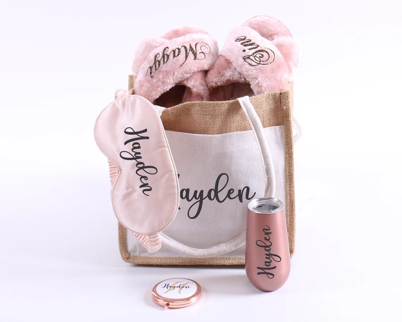 A personalized jute tote bag filled with pink fuzzy slippers, a champagne tumbler, and a satin sleep mask, deluxe Teen Party Favors. Etsy