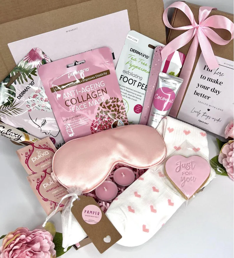 Luxurious pink Galentine's Day Gift spa set with a satin eye mask, face mask, foot peel, heart socks, and cookie. Etsy