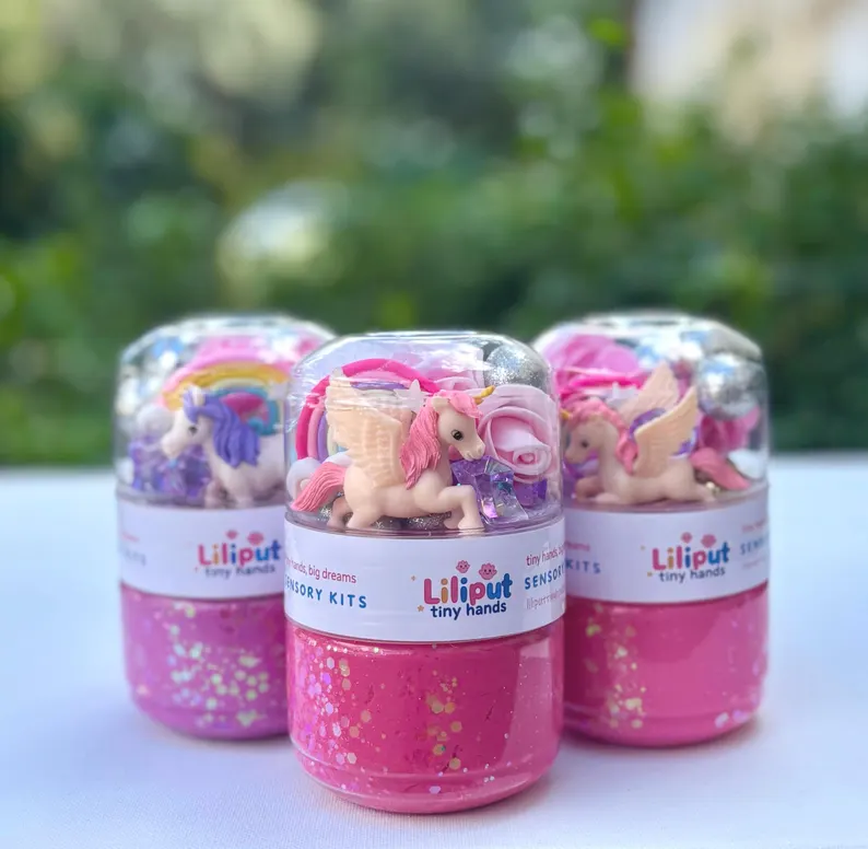 Three pink glitter sensory kits containing unicorn figures and play-doh/slime, perfect as cute Unicorn Party Favors for children.