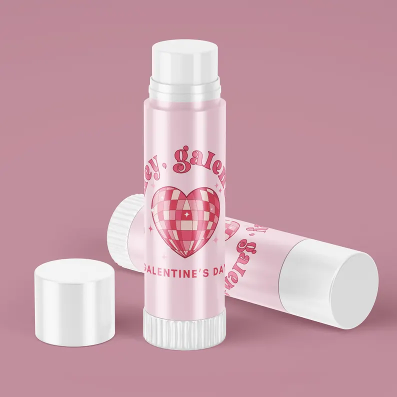 Two pink lip balm sticks featuring a retro disco heart design and "hey, galentine," practical and fun Galentine's Day Party Favors.