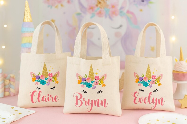 Three personalized natural canvas tote bags with a floral unicorn face design, ideal for customized Unicorn Party Favors. Etsy
