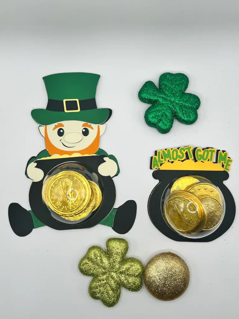 Whimsical leprechaun and pot of gold cardstock cutouts holding gold chocolate coins in clear plastic domes for festive St. Patrick's Day favors.