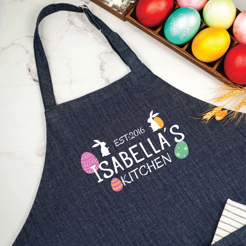 A personalized denim kitchen apron with colorful egg graphics, making a thoughtful custom Easter Hostess Gift.